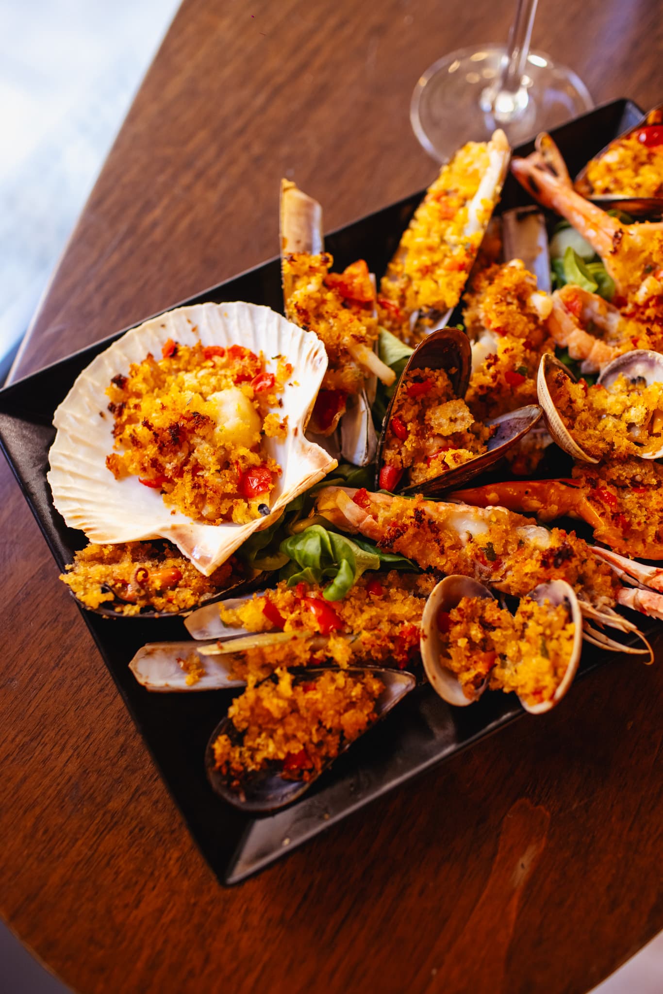 Assorted baked seafood platter: scallops, mussels, prawns, and clams with golden breadcrumbs.